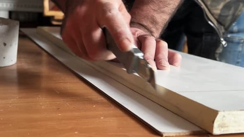 Adult Man Cutting Foam Board with Utility Knife