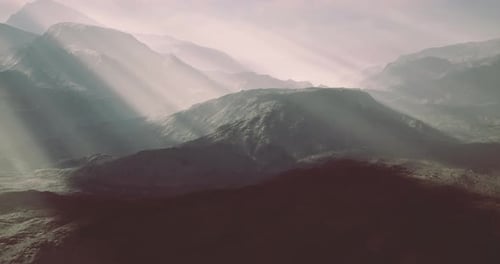 Sun Rays Illuminating Rugged Mountain Landscape During Early Morning Hours