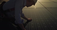 Man Inspecting Solar Panels During Sunrise