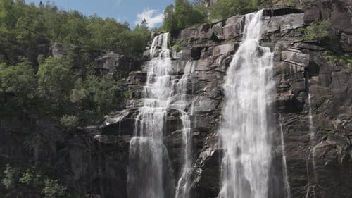 Up to down drone shot of the Skjervsfossen Waterfall located in Norway with a rainbow visible in the