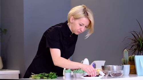Woman Decorates Cupcakes with Berries