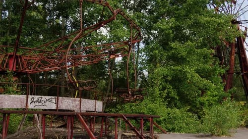 Abandoned swing ride spinning on windy day in Pripyat, zoom out view