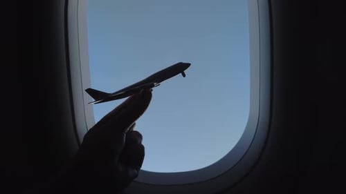 Toy Airplane Held Near the Airplane Window