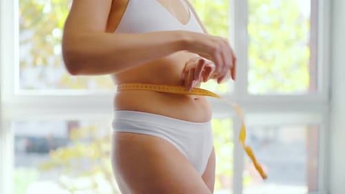 Fitness and Weight Loss Concept Woman Measures Her Body with a Tape Measure