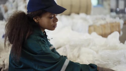 An AfricanAmerican Woman in a Special Uniform Sorts Polyethylene at a Waste Recycling Plant