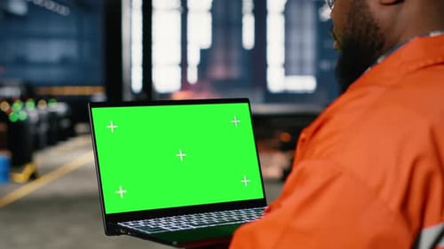 Green Screen Next to Operator Using Laptop and Industrial Equipment
