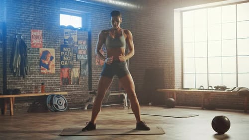 Strong and Fit Beautiful Athletic Woman in Sport Top and Shorts is Doing Squat Exercises in a Loft