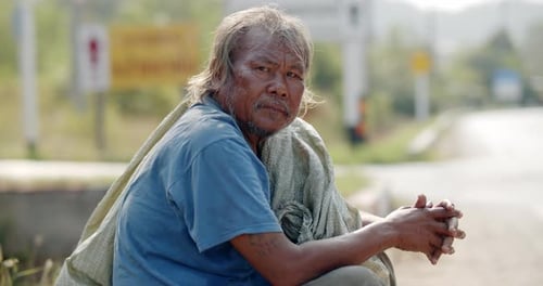 An Asian man who is a poor ragpicker or collects garbage and sells, sitting on the side of the road