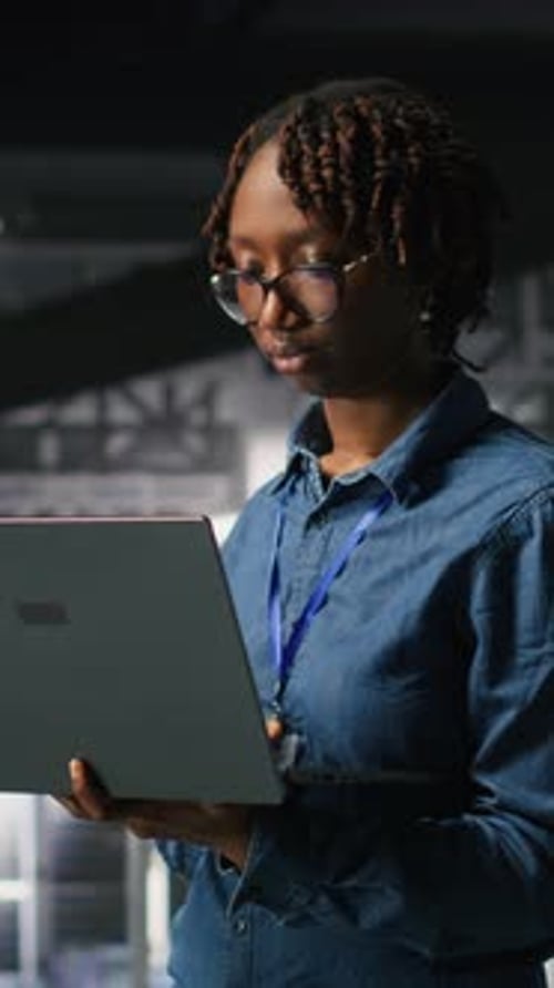 Vertical Video Data Center System Administrators Doing Maintenance Tasks on Laptop