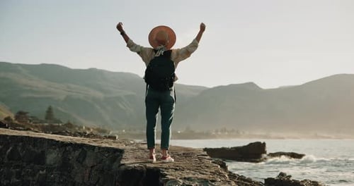 Hiking, back or person at ocean with arms raised, achievement or success in exploration goal