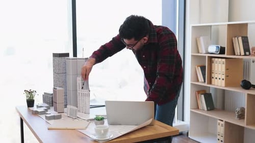 Indian Male Architect Working on Modern City Project with Model Buildings