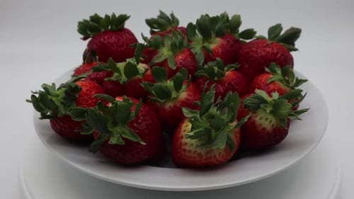 Fresh ripe delicious strawberries in a white bowl rotating