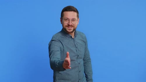 Hombre caucásico que extiende la mano a la cámara ofreciendo un apretón de manos, saludo, invitación de bienvenida