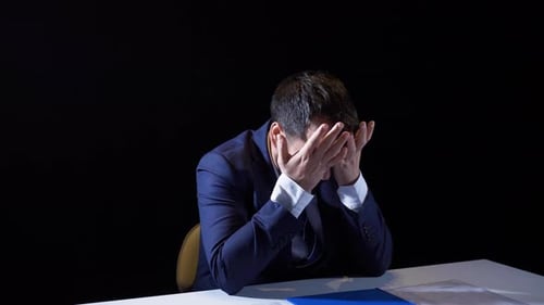 Upset Man in Suit Sits at Table