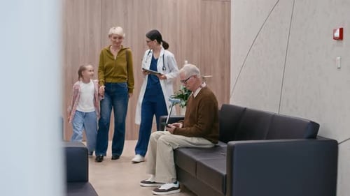 Female Doctor Assisting Multigenerational Patients in Hall of Clinic