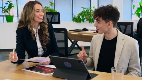 Chef d'équipe féminine discutant des affaires commerciales avec un jeune travailleur à l'aide de graphiques. Réunion d'affaires à