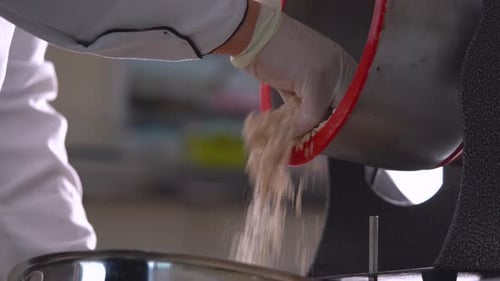 Chef Pouring Granular Mix Into Food Container