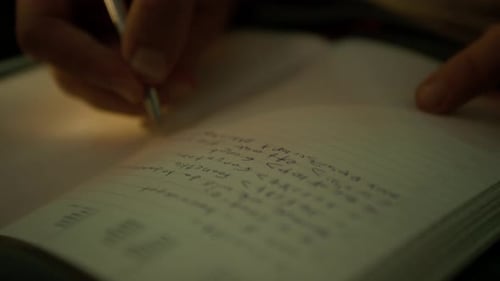 Close-up of Hand Holding Pen and Writing Mathematical Equations in Journal