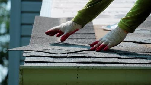 Roofers Putting New Roof Shingles in Right Order on the House Roof Element of Roof Renovation