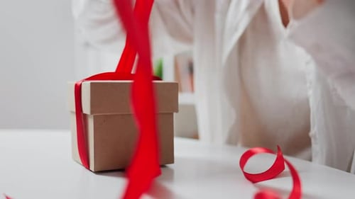 Opening Beautifully Wrapped Gift with Red Ribbon