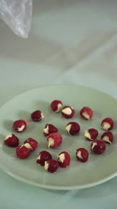 Woman's Hands Stuffing Cream Cheese into Fresh Raspberries