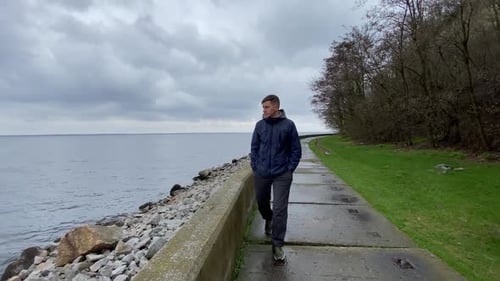 A young man walks by the river, by the sea, along the embankment