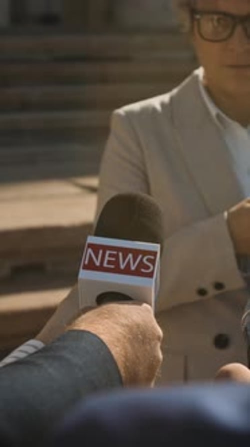 Woman Giving Press Conference to Reporters Holding Microphones