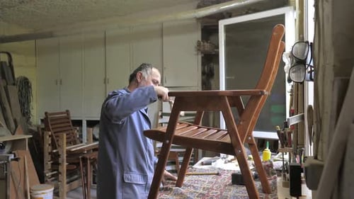 A Carpenter in His Workshop Assembles a Handmade Chair Screws a Bolt Secures It with a Hex Key