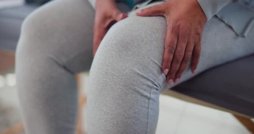 Woman massaging her painful knee in a home setting