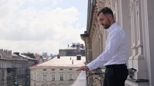 Confident Businessman Fits the Terrace Railing Raises His Head Enjoys Fresh Air