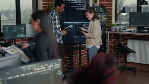 Das Softwareentwicklungsteam vergleicht Codefehler auf dem Wanddisplay mit dem Tablet