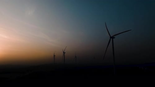 Wind Turbines at Twilight with Golden Hour Sky Renewable Energy Farm Landscape Aerial View of