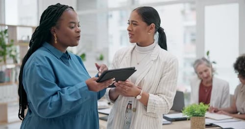 Two Women Discuss Tablet in Modern Office