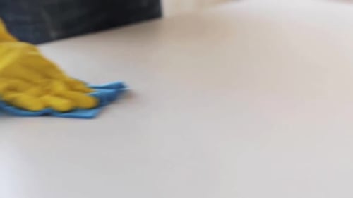 Bright Yellow Glove Cleaning White Surface with Cloth