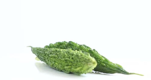 Deux courges amères, melon amer, légume, pivotant à 360 degrés sur fond blanc, vue latérale