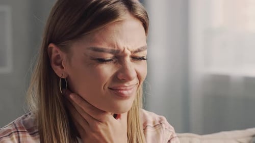 Woman suffering touching neck feeling sore throat at home