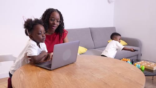 Mother and Children Using Laptop at Wooden Table