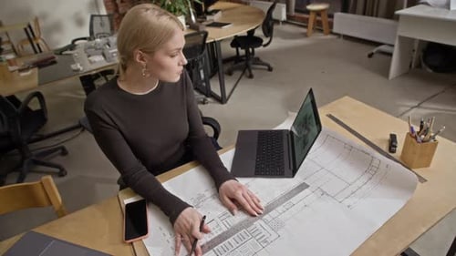 Female Architect Drawing Floor Plan and Reviewing Digital 3D House Model