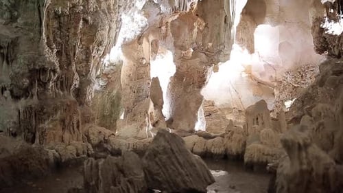 Giant limestone cave underground with white stalactites and stalagmites riding through an illuminate