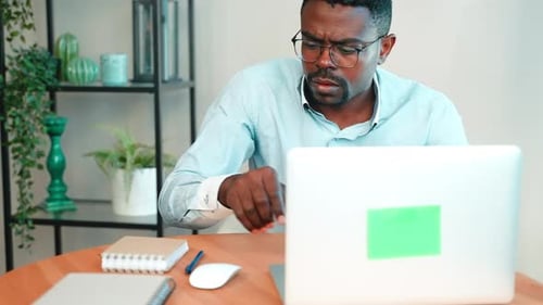 Man Works on Laptop Makes Notes Notepad