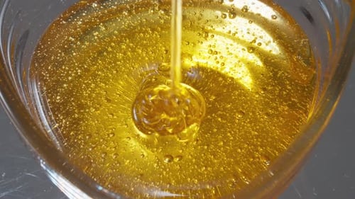 Close Up Honey Pouring into Glass Bowl