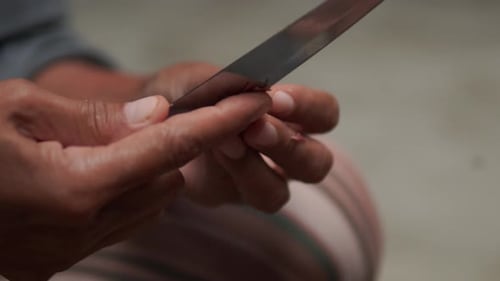 Person is holding a knife to peeling onion skin and cut the onions.