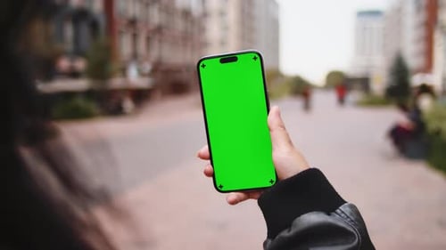 Woman Holding Smartphone with Green Screen in City Street