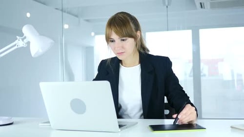 Woman Working on Laptop with Tablet at Desk
