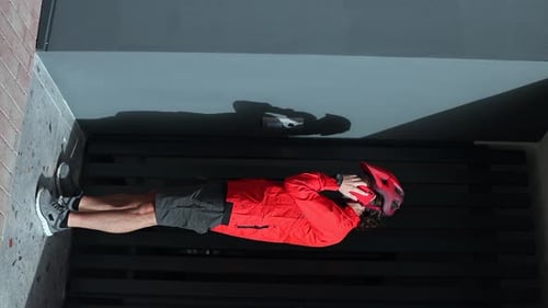 Young Adult Puts on Red Bike Helmet