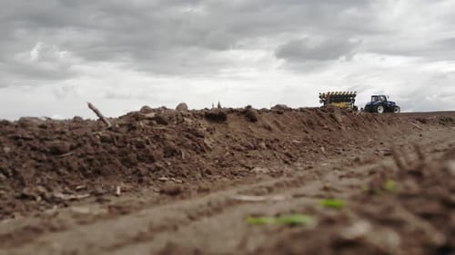 Blue tractor planting sunflower with yellow planter on the field in Ukraine