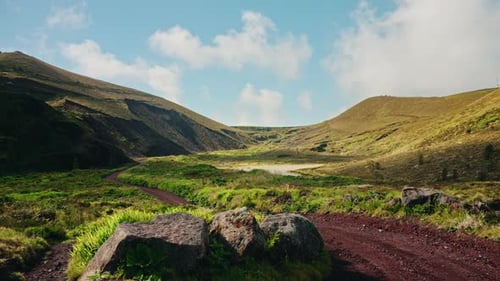 Green picturesque mountain landscape. Scenic rural landmark. Green grass meadow. Blue sky with fluff