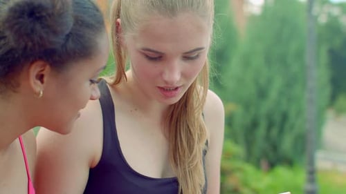 Blonde Girl Talking with Afro Girlfriend in Park. Close Up of Young