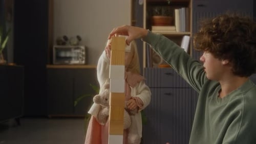 Child Stacking Wooden Blocks Building Tall Tower with Brother