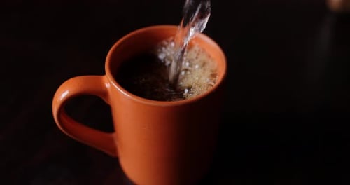 Pouring Water into Hot Black Coffee Mug
